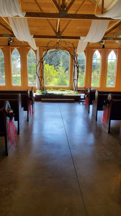 Rustic indoor Viking wedding ceremony aisle with wooden arch and draped fabric decor