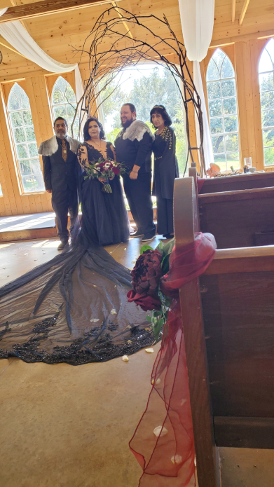 Viking wedding group portrait with bride, groom, and family under rustic wooden arch