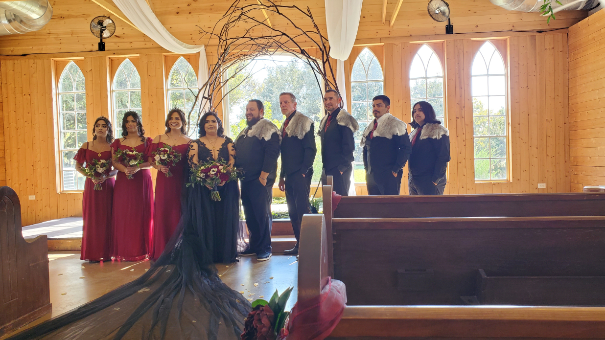 Viking wedding party in formal attire inside chapel with wooden arch ceremony backdrop