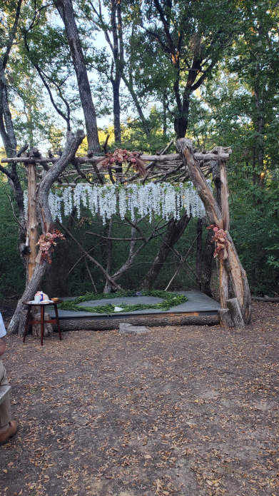 Outdoor Viking wedding altar with rustic wooden structure and hanging floral decor
